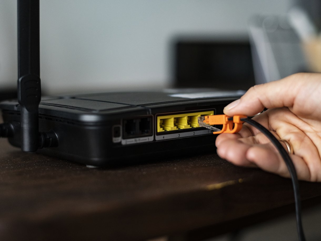 Mano conectando un cable de red a un router